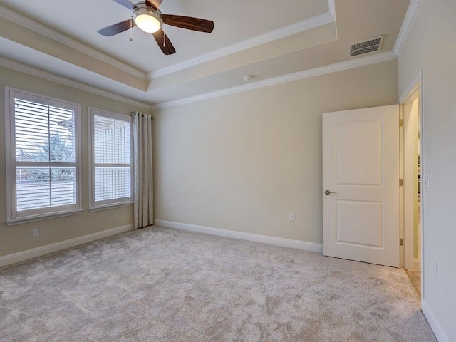 spare room featuring light colored carpet, ornamental molding, and a tray ceiling