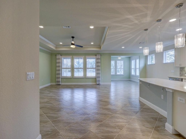 unfurnished living room with a raised ceiling, ornamental molding, and ceiling fan