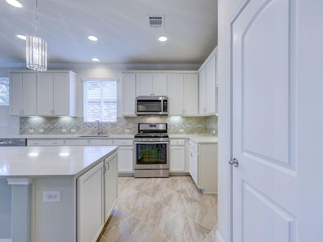 kitchen with stainless steel appliances, white cabinetry, sink, and decorative light fixtures