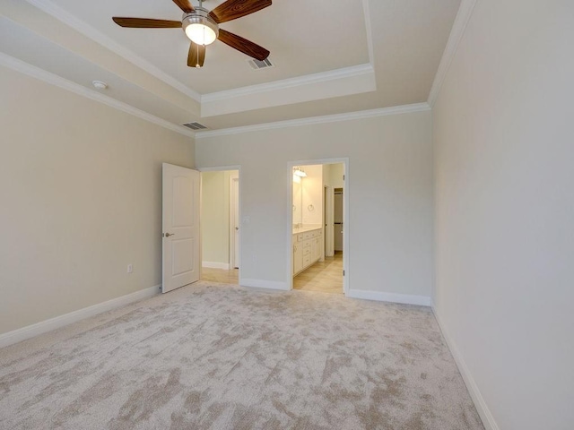 unfurnished bedroom with a tray ceiling, connected bathroom, crown molding, and ceiling fan