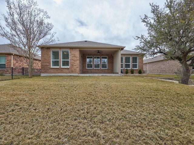 rear view of property featuring ceiling fan and a lawn