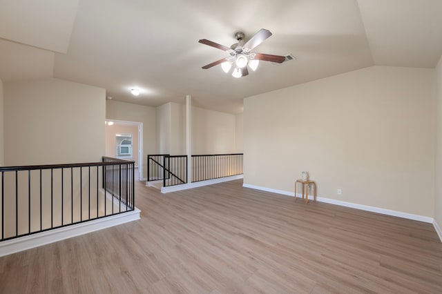 empty room with ceiling fan, lofted ceiling, and light hardwood / wood-style flooring