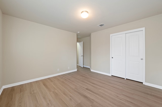 unfurnished bedroom featuring light hardwood / wood-style flooring and a closet