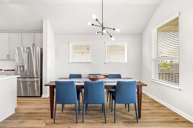 dining room featuring lofted ceiling, an inviting chandelier, and light hardwood / wood-style floors