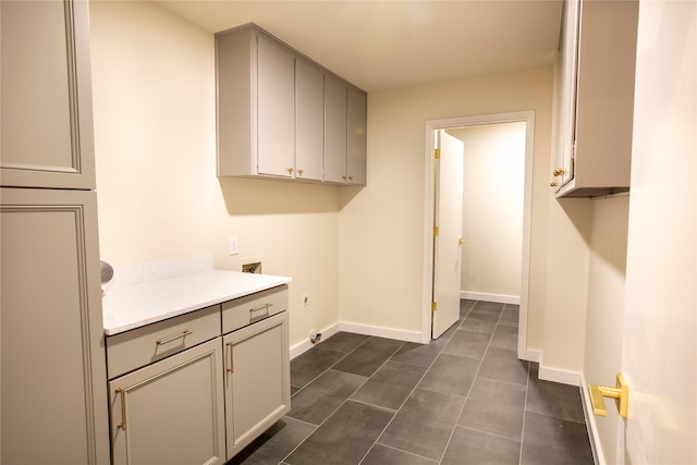 laundry room with dark tile patterned flooring, hookup for a washing machine, and cabinets