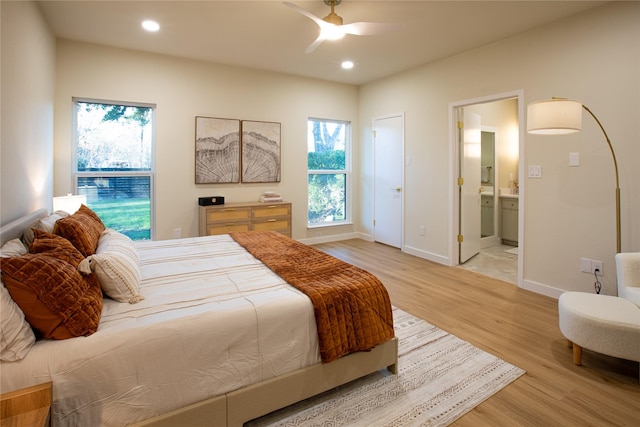 bedroom featuring light wood-type flooring, ceiling fan, and ensuite bathroom