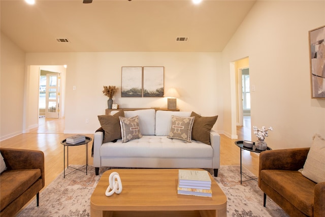 living room with plenty of natural light, vaulted ceiling, and light wood-type flooring