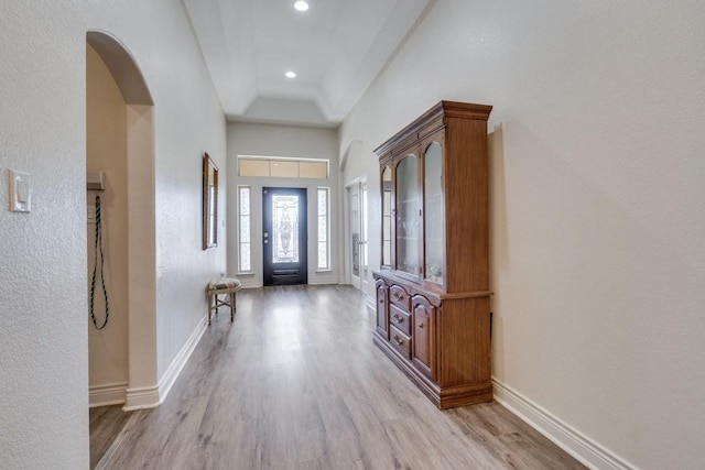 entryway with light wood-type flooring and a tray ceiling