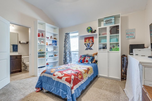 bedroom featuring connected bathroom, vaulted ceiling, and light colored carpet