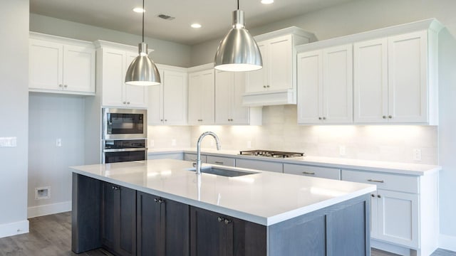 8612 Ambergill Ct, Austin, TX 78744 - kitchen featuring appliances with stainless steel finishes, white cabinetry, tasteful backsplash, dark wood-style flooring, and recessed lighting