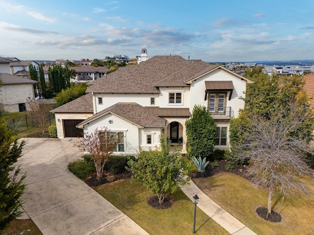 view of front of house featuring a garage, a front lawn, and a balcony