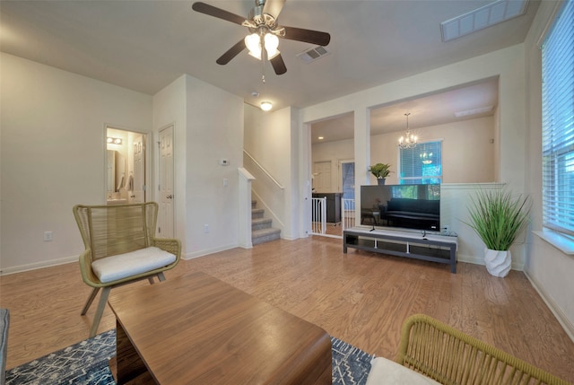 living room with ceiling fan with notable chandelier and hardwood / wood-style floors