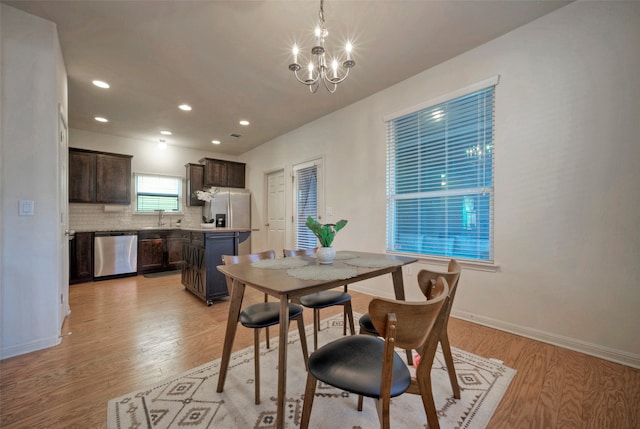 dining area featuring sink, light hardwood / wood-style floors, and a chandelier