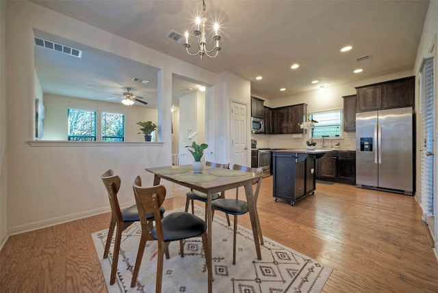 dining area featuring ceiling fan with notable chandelier, sink, and light hardwood / wood-style flooring