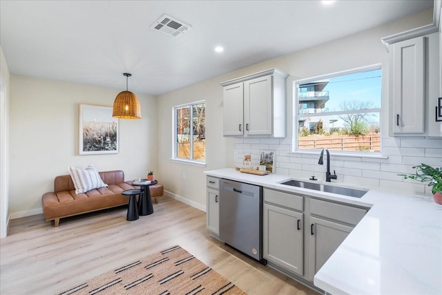 kitchen with tasteful backsplash, dishwasher, sink, gray cabinetry, and hanging light fixtures