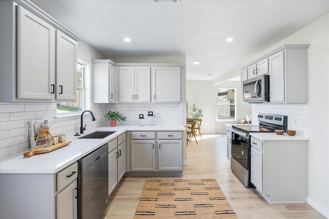 kitchen with stainless steel appliances, a healthy amount of sunlight, sink, and gray cabinetry