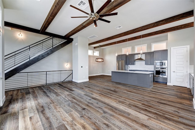 unfurnished living room with beam ceiling, dark wood-type flooring, and ceiling fan