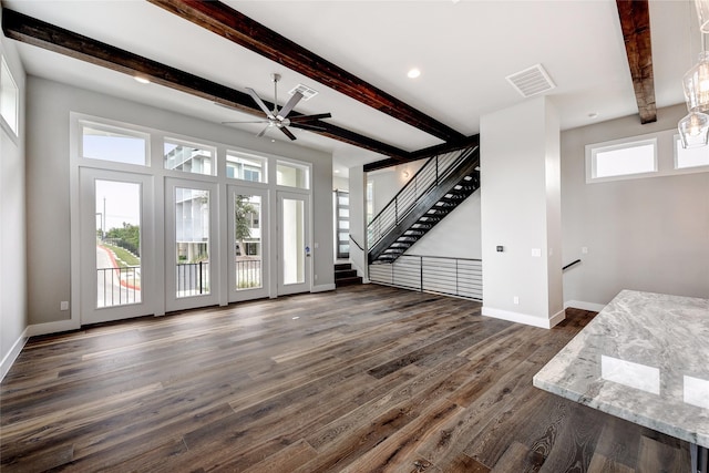 unfurnished living room featuring beam ceiling, a wealth of natural light, and dark hardwood / wood-style floors