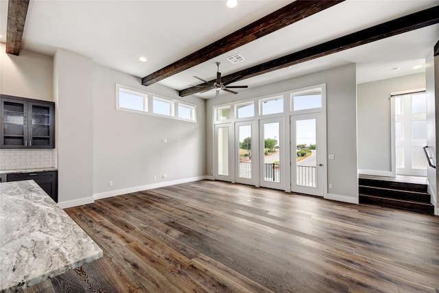 unfurnished living room with beamed ceiling, ceiling fan, and dark hardwood / wood-style floors