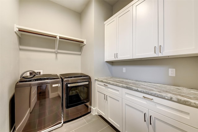 clothes washing area with cabinets, light tile patterned floors, and washer and clothes dryer