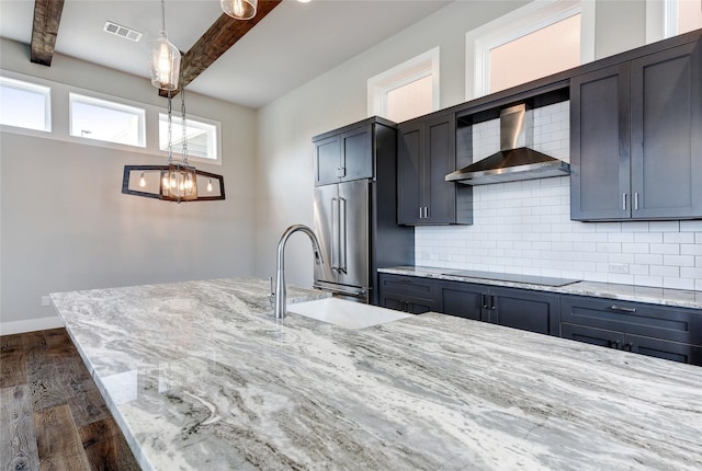 kitchen featuring wall chimney range hood, tasteful backsplash, light stone countertops, black electric cooktop, and beamed ceiling