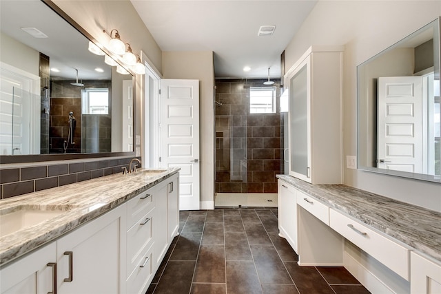 bathroom with vanity, tile patterned flooring, decorative backsplash, and a tile shower