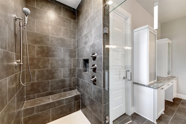 bathroom with an enclosed shower and tile patterned flooring