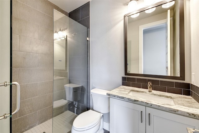 bathroom featuring vanity, toilet, an enclosed shower, and decorative backsplash