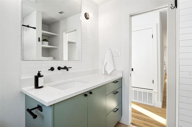 bathroom featuring hardwood / wood-style flooring, vanity, and backsplash