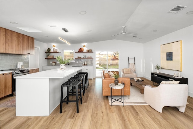 kitchen with white cabinetry, a center island, light hardwood / wood-style flooring, a kitchen breakfast bar, and stainless steel electric stove