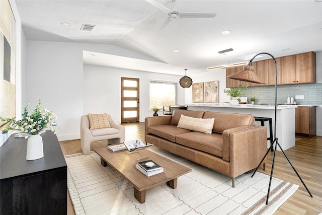 living room featuring light hardwood / wood-style flooring, ceiling fan, and vaulted ceiling