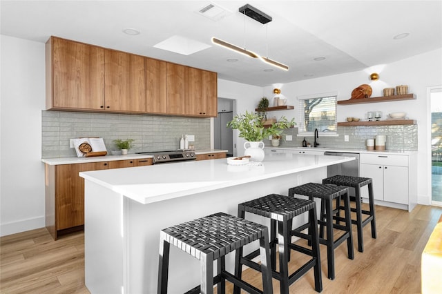 kitchen featuring light wood-type flooring, a kitchen island, white cabinets, and a kitchen bar