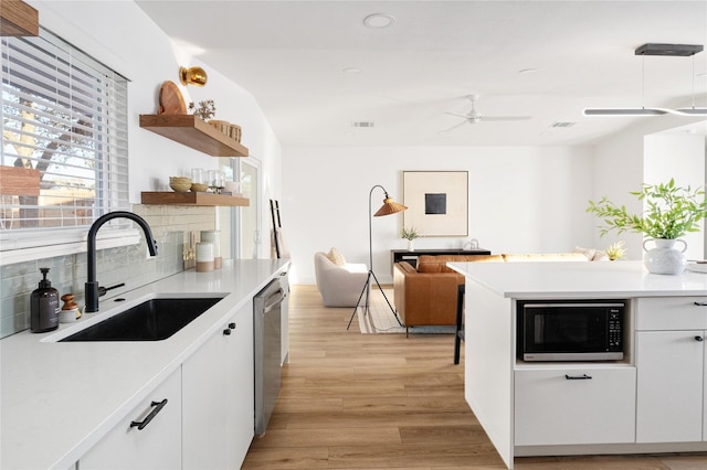 kitchen with sink, white cabinets, decorative backsplash, stainless steel dishwasher, and light hardwood / wood-style floors