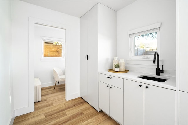 bar featuring white cabinetry, plenty of natural light, sink, and light wood-type flooring