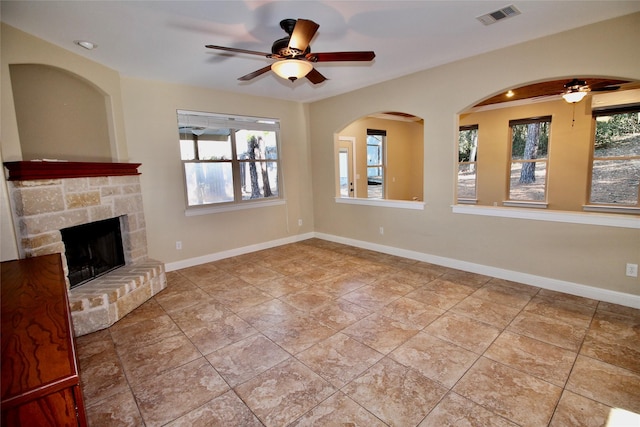 unfurnished living room featuring a stone fireplace, ceiling fan, and light tile patterned flooring