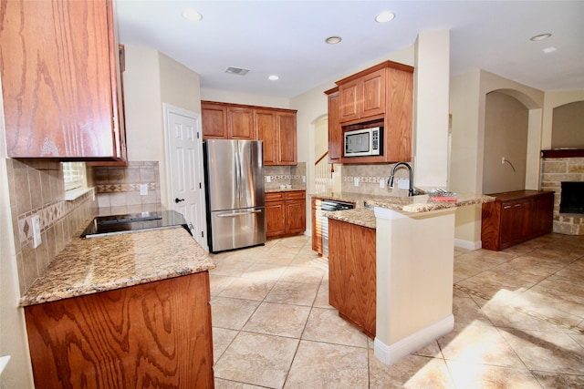 kitchen featuring decorative backsplash, stainless steel appliances, kitchen peninsula, and light stone countertops