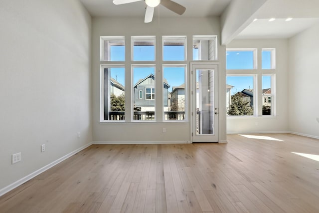 spare room featuring ceiling fan, light hardwood / wood-style floors, and a towering ceiling