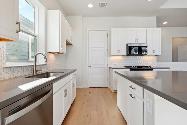 kitchen featuring white cabinetry, sink, light wood-type flooring, and appliances with stainless steel finishes