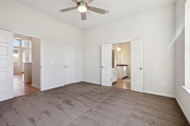 unfurnished bedroom featuring ceiling fan, ensuite bathroom, and carpet flooring