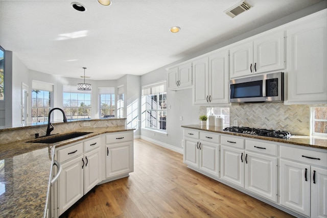 kitchen featuring black gas cooktop, decorative light fixtures, sink, dark stone countertops, and white cabinets