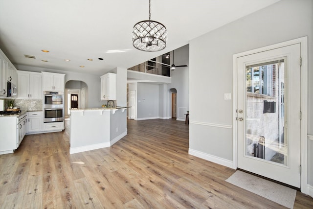 kitchen featuring white cabinetry, tasteful backsplash, a chandelier, appliances with stainless steel finishes, and pendant lighting