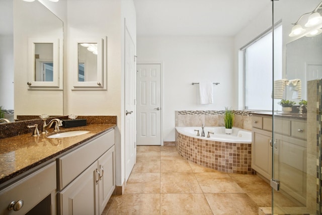 bathroom featuring a relaxing tiled tub, vanity, and tile patterned flooring