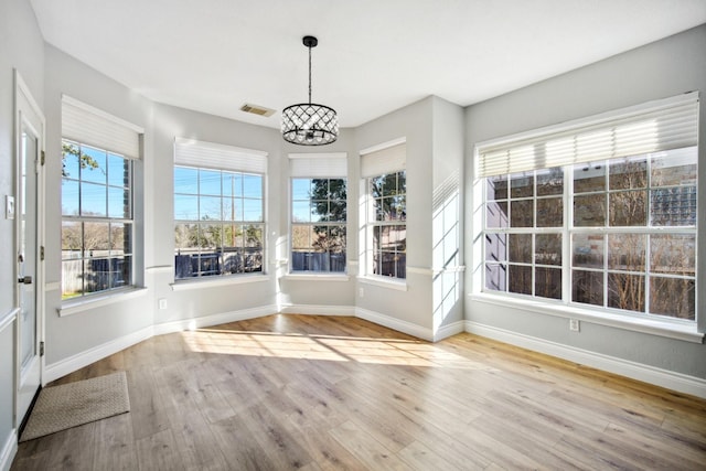 unfurnished sunroom with a healthy amount of sunlight and a notable chandelier