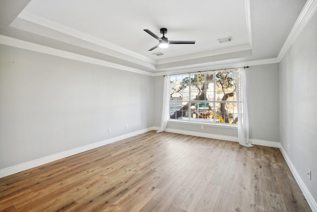 unfurnished room with crown molding, a tray ceiling, and light wood-type flooring