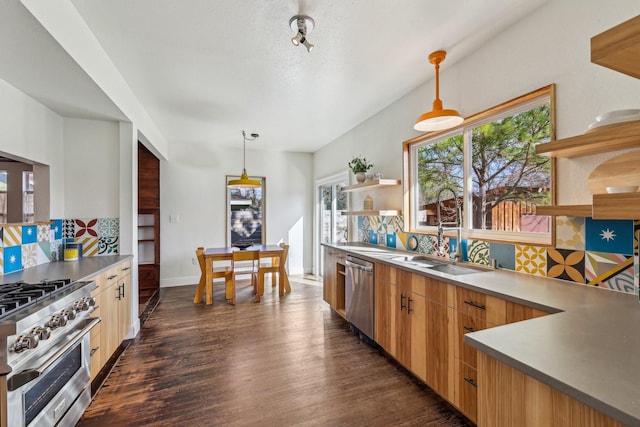 kitchen featuring dark wood-type flooring, sink, tasteful backsplash, hanging light fixtures, and appliances with stainless steel finishes