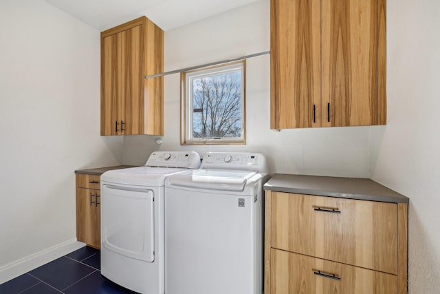 washroom featuring separate washer and dryer, dark tile patterned flooring, and cabinets