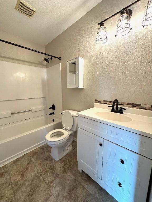 full bath featuring shower / bath combination, toilet, visible vents, vanity, and a textured wall