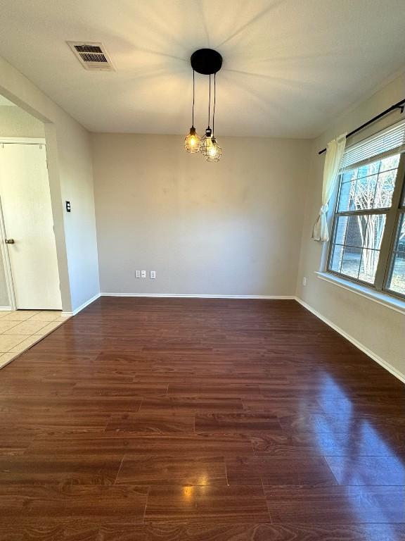 empty room with baseboards, visible vents, and wood finished floors