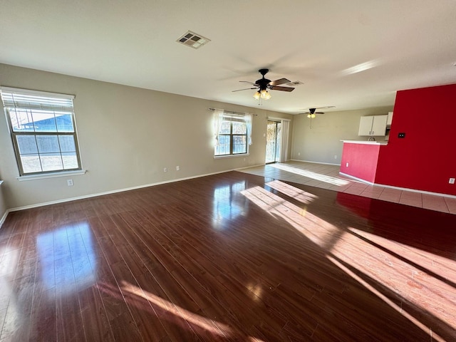 empty room with dark hardwood / wood-style floors, a wealth of natural light, and ceiling fan