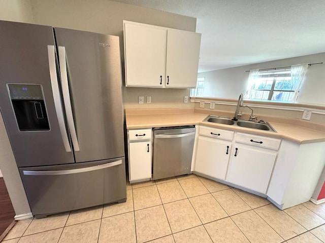 kitchen featuring light tile patterned floors, a sink, white cabinets, light countertops, and appliances with stainless steel finishes